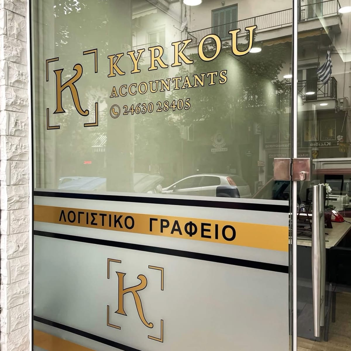 Η βιτρίνα του γραφείου στη Νοσοκομείου 11: το σήμα Kyrkou Accountants και το τηλέφωνο χαραγμένα στο τζάμι, και από κάτω η ζώνη «Λογιστικό Γραφείο».